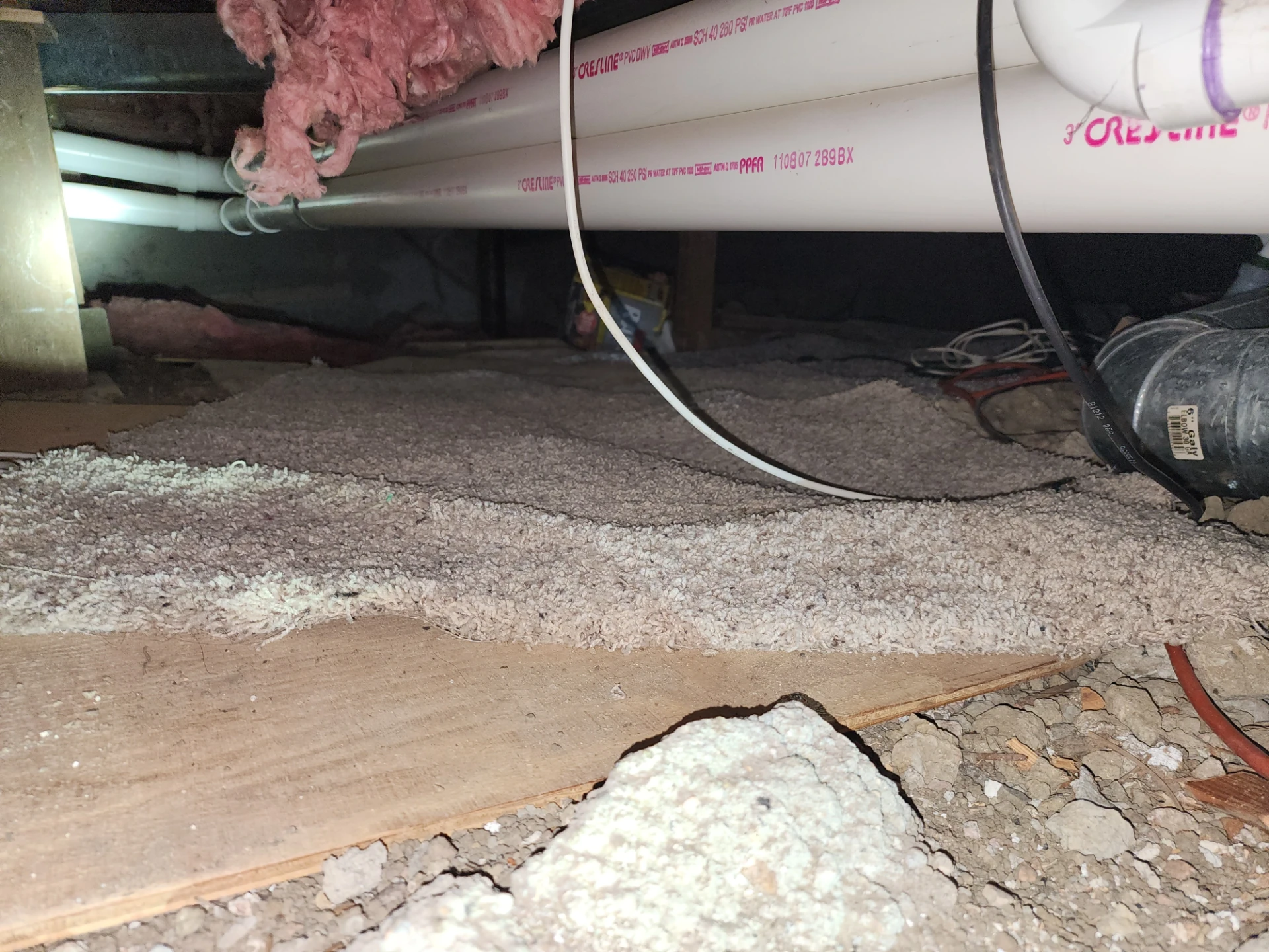 Original crawl space interior before basement conversion, showing low clearance and plumbing