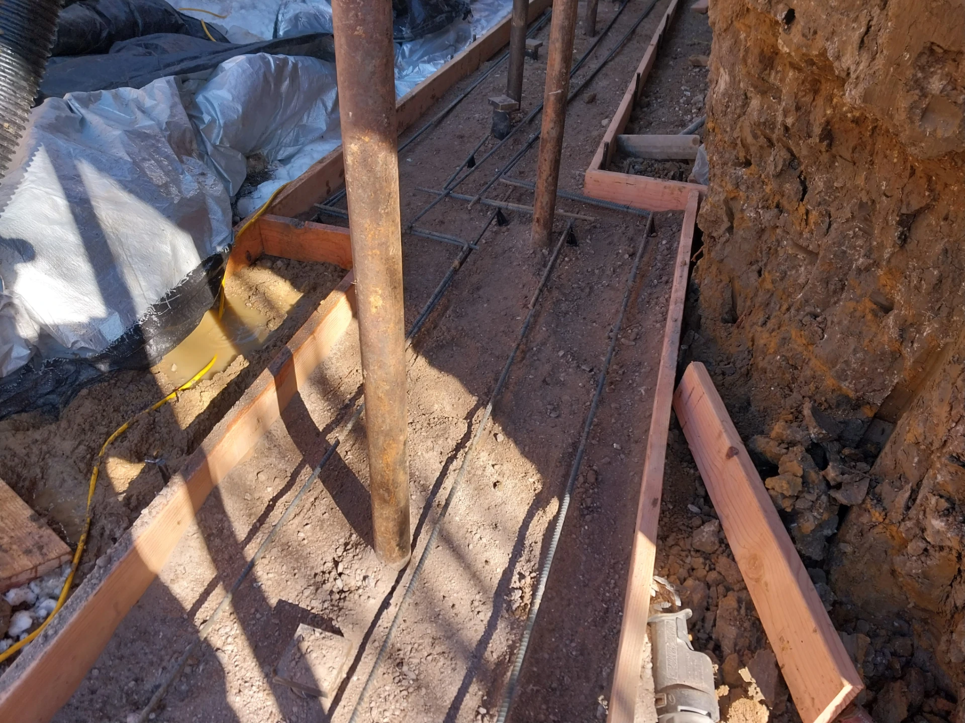 Rebar and wood forms for new foundation footing during basement conversion