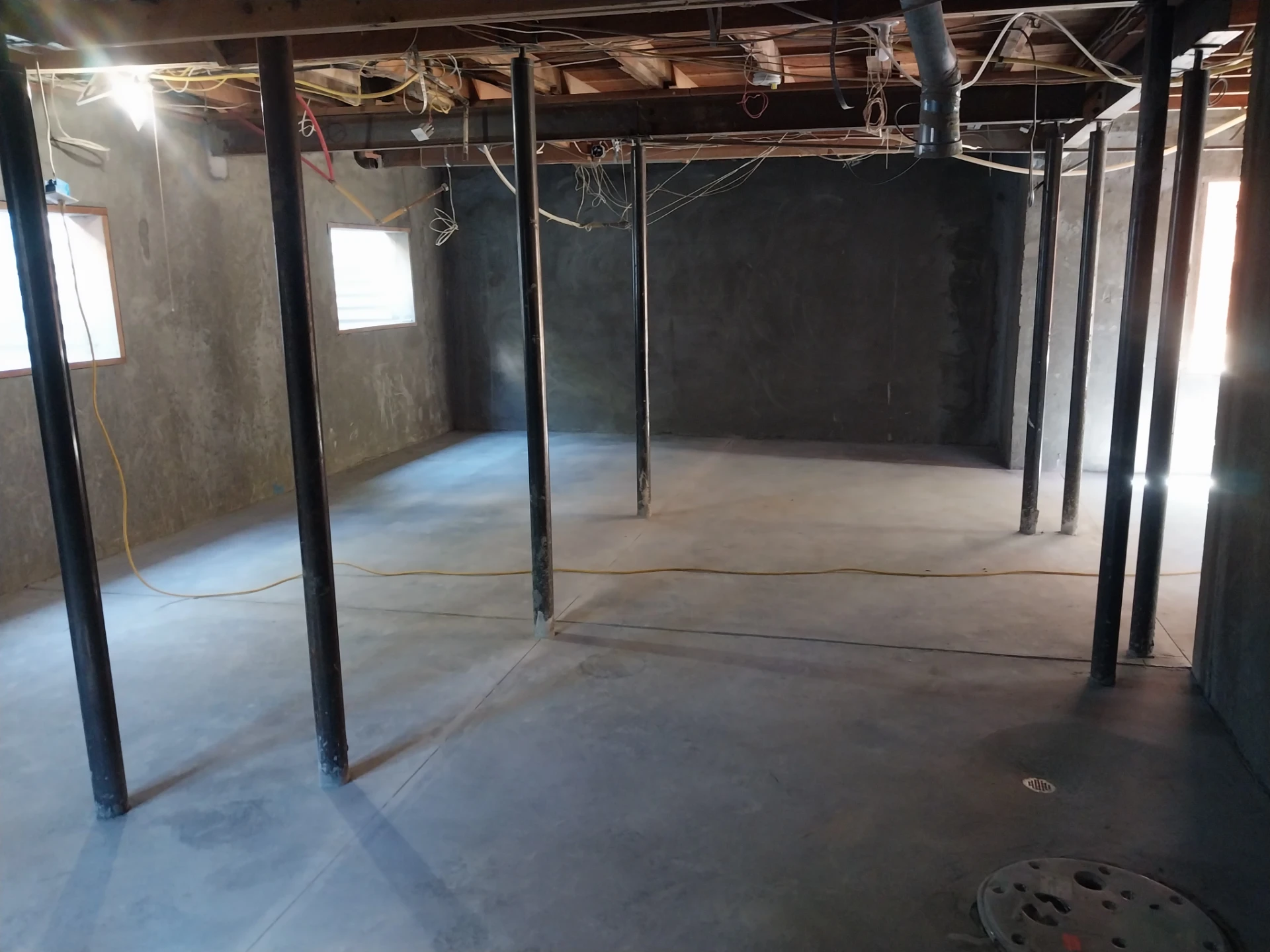 Basement interior mid-construction with support posts, before ceiling and wiring